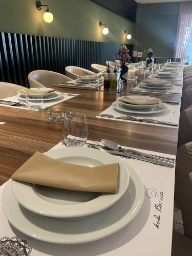 a long table with white plates and napkins on it at Hotel Restaurant Kod Barića in Grude