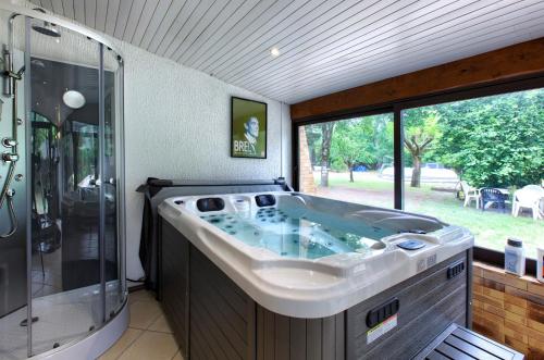 een groot bad in een badkamer met een raam bij Villa Rodolphe 8 in Le Pian-Médoc