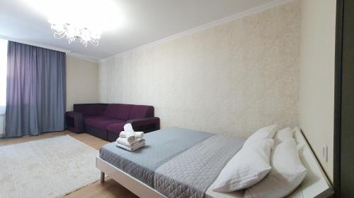 a bedroom with a bed and a purple couch at 19 2х комн с 2 мя кроватями и раскладной диван,2 санузла 1- 6 человек,возле Байтерека in Astana