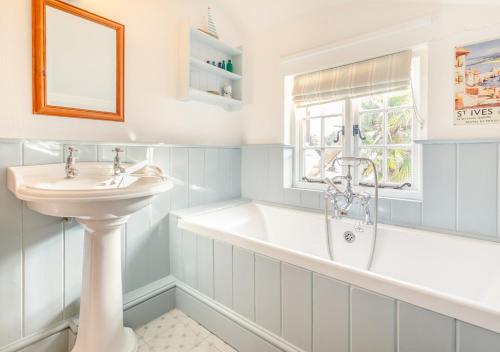 ein Badezimmer mit einer Badewanne und einem Waschbecken in der Unterkunft Popigale Cottage in Helford