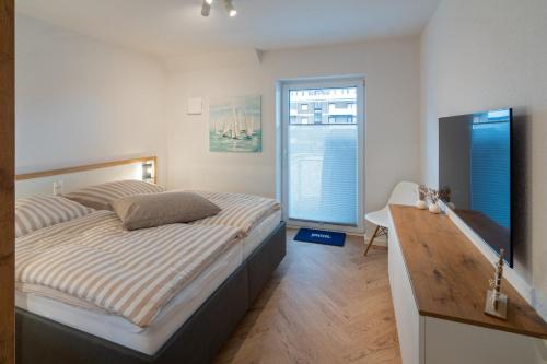 une chambre avec un lit, un bureau et une fenêtre dans l'établissement Ahoi, à Dornumersiel