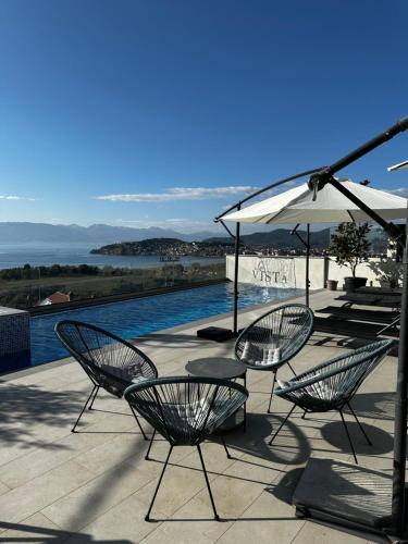 a patio with chairs and an umbrella and a pool at La Vista Luxury Villa in Ohrid
