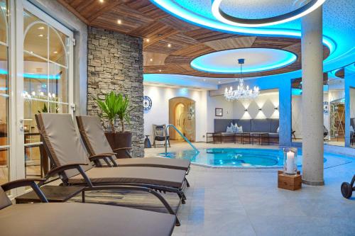 a pool room with chairs and a swimming pool at Platzlhof - Mein Hotel im Zillertal in Ried im Zillertal