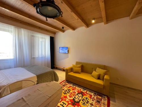 a bedroom with two beds and a couch and a window at Ski in Ski out Slopeside apartments just 50 meters from the Gondola in New Gudauri in Gudauri