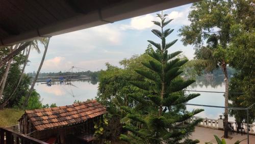 a palm tree next to a river with a house at Ambadi's villa -Lake view resort in Pallipuram