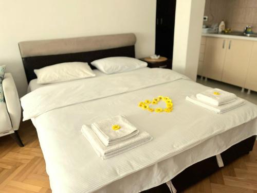 a bed with two white towels and yellow flowers on it at Center Apartment in Višegrad