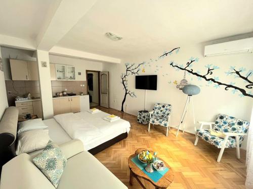 een woonkamer met een witte bank en een muurschildering van bomen bij Center Apartment in Višegrad