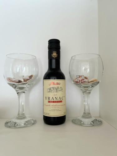 a bottle of wine next to two wine glasses at Center Apartment in Višegrad