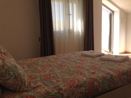 Bett in einem Zimmer mit Fenster in der Unterkunft Figueira Praia Buarcos in Figueira da Foz