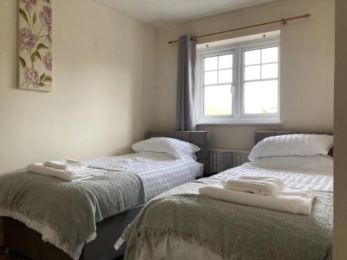 two beds in a room with towels on them at Quiet 3 bed semi with off street parking in Bingham