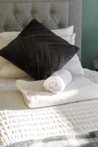 a bed with a black and white pillow and towels at Quiet 3 bed semi with off street parking in Bingham