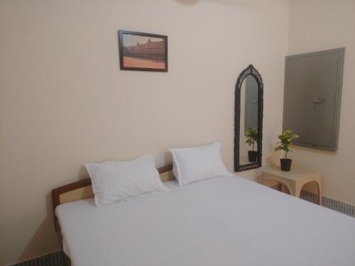 a white bed with two white pillows and a mirror at Red king home stay in Bikaner
