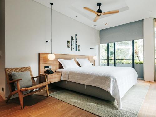 een slaapkamer met een bed en een stoel en een plafondventilator bij Joy Villa in Sailing Club Phu Quoc - 3BR with private pool in Phu Quoc