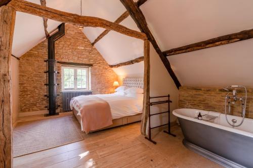 een slaapkamer met een bed en een bad in een kamer bij Coach House, Cold Aston in Bourton on the Water