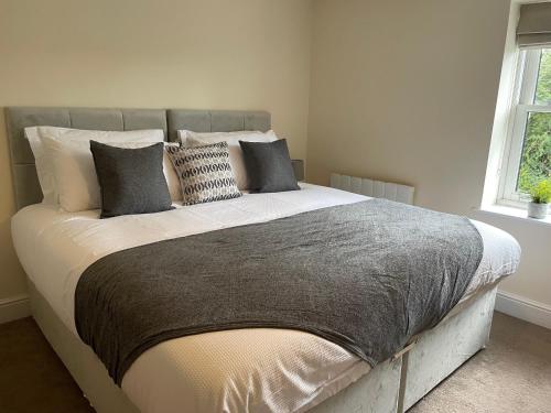 a bedroom with a large bed with many pillows at 2 Cherry Tree Cottages in Stock