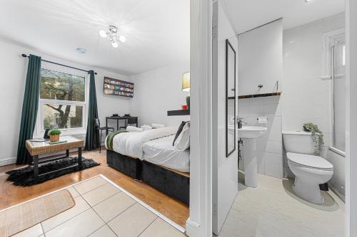 a bedroom with a bed and a toilet and a sink at Charis City Abode in London