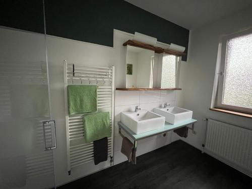 a bathroom with two sinks and a mirror at Ferienwohnung "Wallheckenblick Schatteburg", 95159 in Rhauderfehn