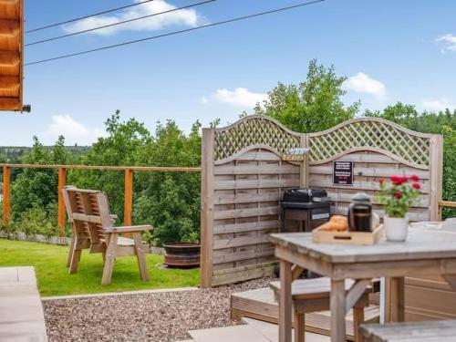 a patio with a grill and a table and a chair at Lochinvar - Clydesdale Log Cabin with Hot Tub in Airdrie