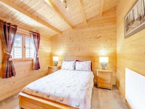 een slaapkamer met een bed in een blokhut bij Lochinvar - Clydesdale Log Cabin with Hot Tub in Airdrie