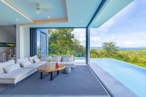 sala de estar con sofá, mesa y piscina en Yamu Hills Panoramic Ocean View 6 Bed Luxury Pool Villa - Phuket, en Phuket