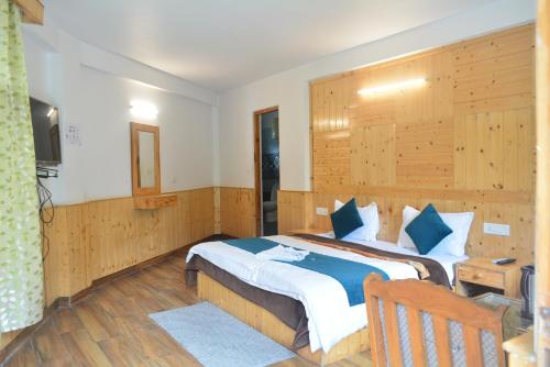 a bedroom with a large bed with a wooden wall at Hotel Neelgiri - Manali Diaries in Manāli
