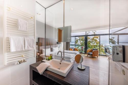 een badkamer met een wastafel en een grote spiegel bij aika seaside living hotel in Friedrichshafen
