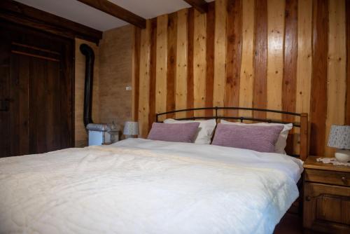 a bed in a room with a wooden wall at Počitniška hiša Koča Dobnik in Lovrenc na Pohorju