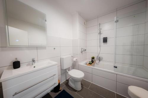 a white bathroom with a toilet and a tub and a sink at Come4Stay Passau - Apartment Seidenhof I voll ausgestattete Küche I Balkon I Badezimmer in Passau