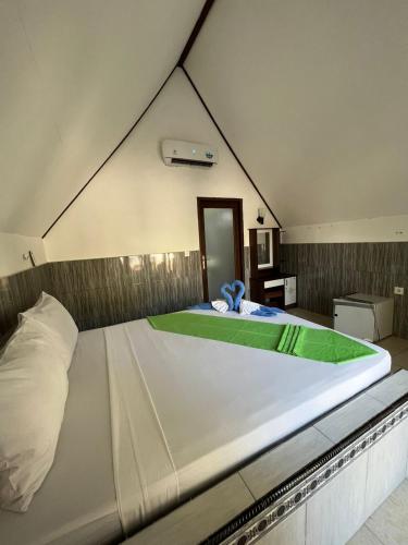 a bedroom with a large white bed in a room at Meno Melani guesthouse in Gili Meno