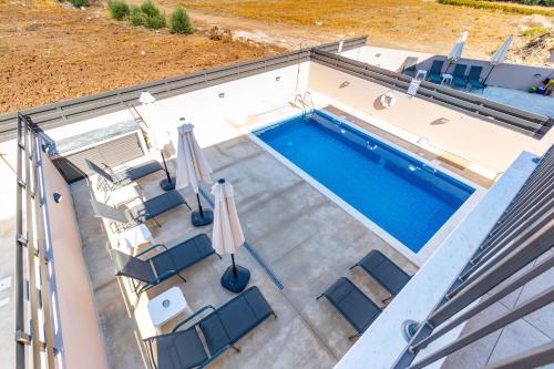 an overhead view of a swimming pool with chairs and an umbrella at Villa Elpida TWO by Ezoria Villas in Timi, Paphos in Ktima