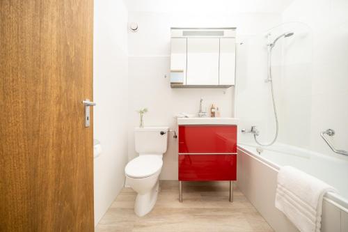 uma casa de banho com um WC branco e um armário vermelho em 4103 Charmantes, neu renoviertes Studio em Vulpera