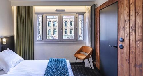 a bedroom with a bed and a chair and a window at Best Western Plus Hotel Cargo in Dunkerque