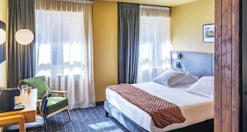 a hotel room with a bed and a desk and window at Best Western Plus Hotel Cargo in Dunkerque