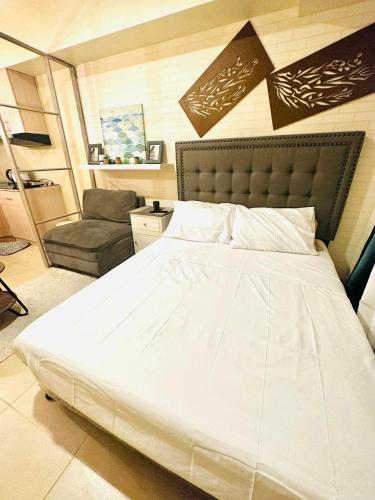 a bedroom with a large white bed and a chair at Avida Riala Tower 1, 2nd Floor in Cebu City