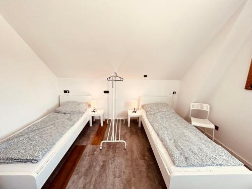 two beds in a room with white walls and wooden floors at Cozy Apartment near Hamburg in Stelle