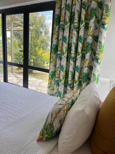 a bed with two pillows in front of a window at COCO MANGO Villa in Trèfles