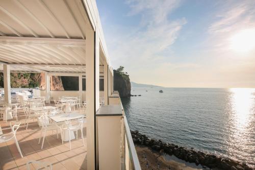 a balcony with tables and chairs overlooking the water at Hotel Giosue' a mare Sorrento in Meta