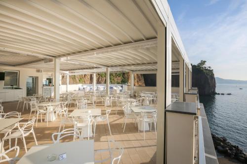 a restaurant with tables and chairs and the water at Hotel Giosue' a mare Sorrento in Meta