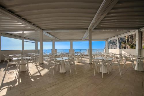 a room with tables and chairs with the ocean in the background at Hotel Giosue' a mare Sorrento in Meta