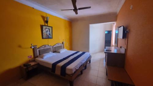 a bedroom with a bed and a yellow wall at HOTEL CITADEL in Vasco Da Gama