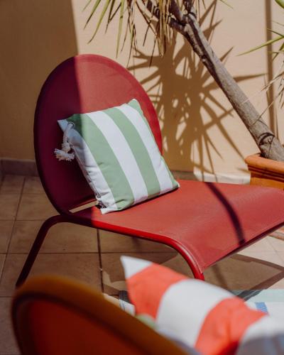 a red chair with a green and white pillow on it at Hotel Le Grimaldi by Happyculture in Nice