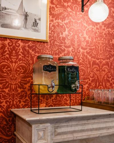 two jars on a table in a room with red wallpaper at Hotel Le Grimaldi by Happyculture in Nice