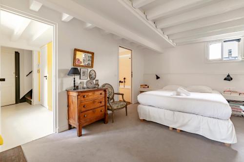 une chambre avec un lit, une commode et un miroir dans l'établissement Veeve - Montparnasse Medley, à Paris