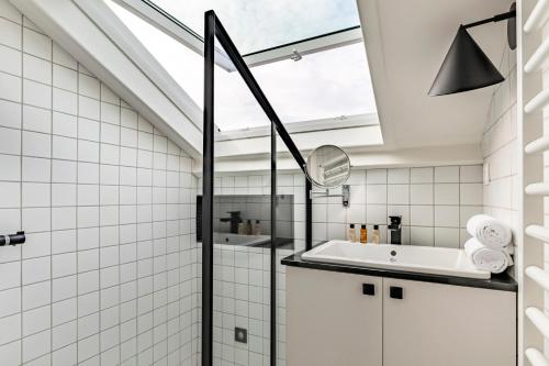 La salle de bains est pourvue d'une baignoire, d'un lavabo et d'une lucarne. dans l'établissement Veeve - Montparnasse Medley, à Paris