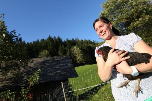 a woman holding a chicken in front of a fence at Biohof Teufel in Lunz am See