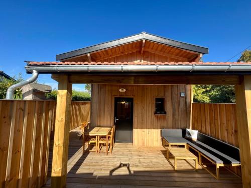 eine Holzterrasse mit einer Bank und einem Tisch in der Unterkunft La cabane du Broustic in Andernos-les-Bains