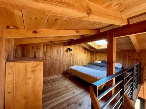 ein Schlafzimmer mit einem Bett in einer Holzhütte in der Unterkunft La cabane du Broustic in Andernos-les-Bains