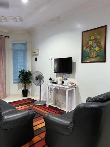 Sala de estar con 2 sofás y TV en Tok Wan Roomstay en Kampong Banggol Binjai