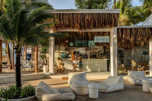 a store with chairs and palm trees in front of it at Arinara Beach Resort Phuket - SHA Extra Plus in Bang Tao Beach