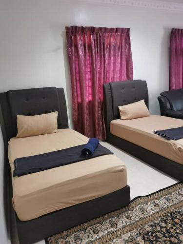 dos camas sentadas una al lado de la otra en una habitación en Tok Wan Roomstay en Kampong Banggol Binjai